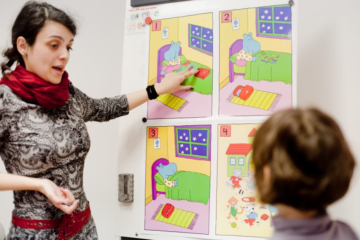 Profesoară Echo Kids explicând un exercițiu unui copil, folosind fișe ilustrate