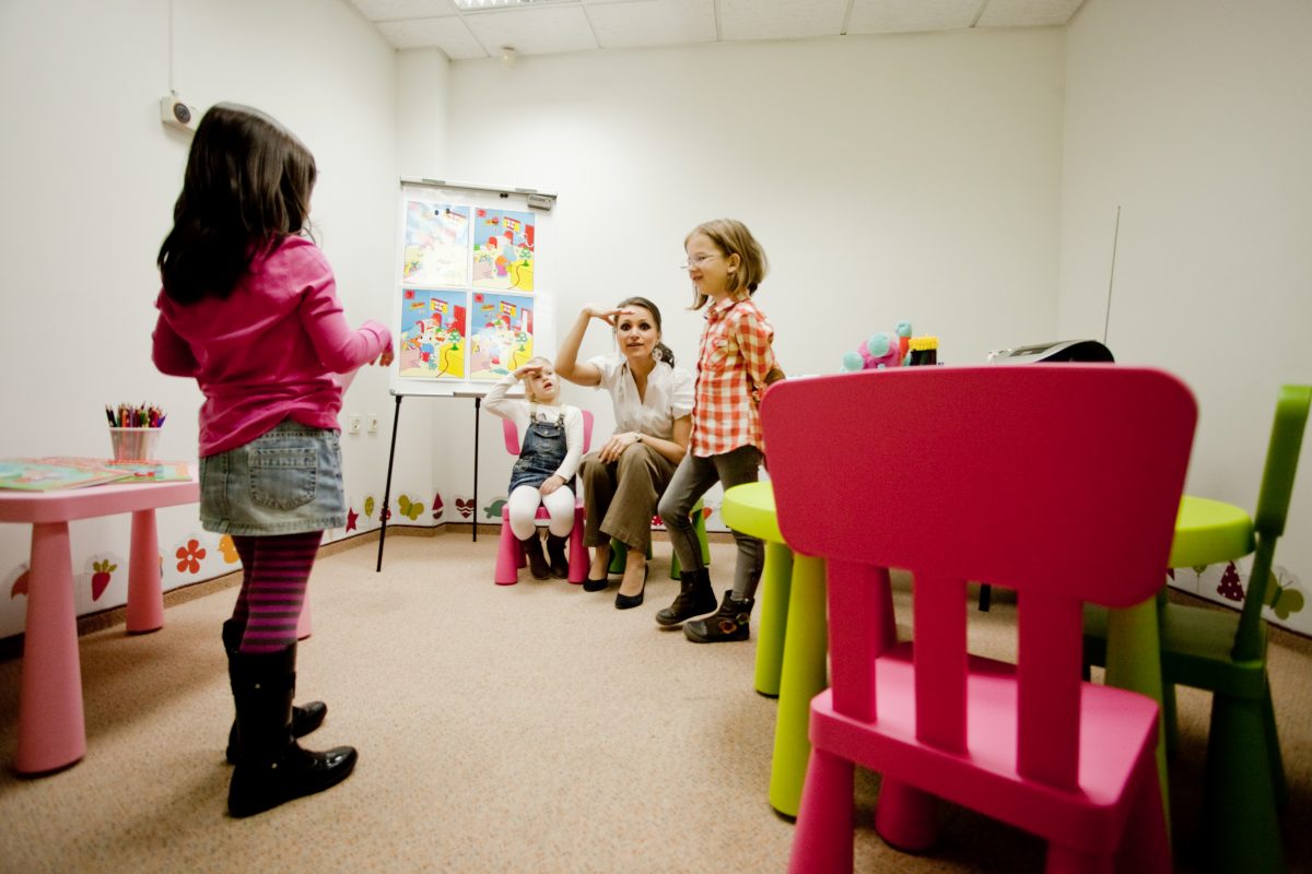 Profesoară Echo Kids așezată la nivelul copiilor, în timpul unei activități de grup